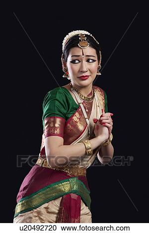 Stock Image - Scared Bharatanatyam dancer performing over black background. Fotosearch
