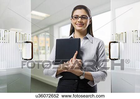 Secretary holding a laptop in the office View Large Photo Image Stock Image - Secretary holding a laptop in the office . Fotosearch