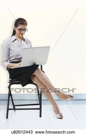 Secretary sitting on a chair with a laptop View Large Photo Image Stock Image - Secretary sitting on a chair with a laptop . Fotosearch