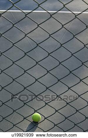 Stock Photo - Shot of tennis ball lying on ground in front of net . Fotosearch
