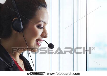 Stock Photo - Side view of female customer service representative in office. Fotosearch