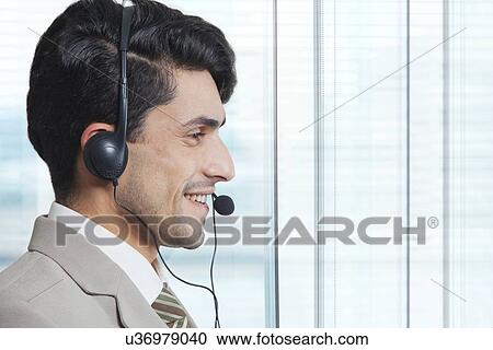 Side view of male customer service representative wearing headset in office View Large Photo Image Stock Image - Side view of male customer service representative wearing headset in office. Fotosearch