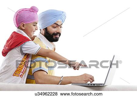 Sikh boy pointing at his fathers laptop View Large Photo Image Stock Photo - Sikh boy pointing at his fathers laptop . Fotosearch