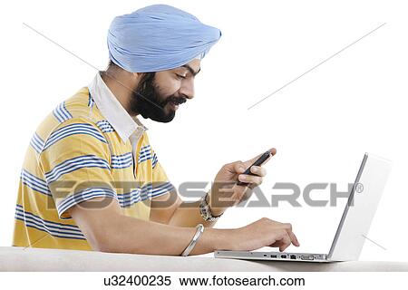Stock Photography - Sikh man with a mobile phone and a laptop . Fotosearch