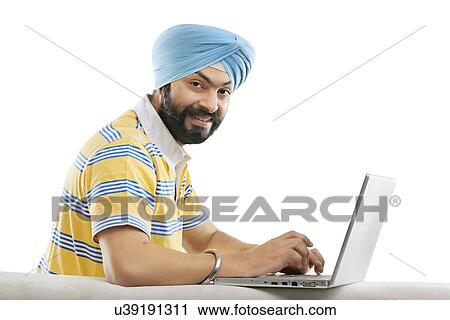 Stock Image - Sikh working on a laptop . Fotosearch