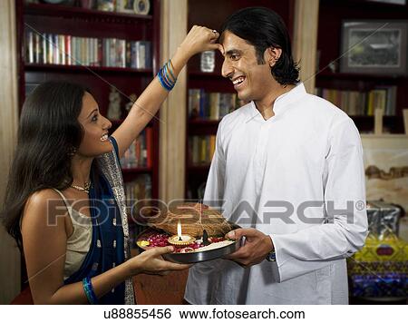 Stock Photograph - Sister applying tika on brother's head . Fotosearch