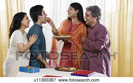 Stock Photo - Sister feeding her brother during Rakhi . Fotosearch