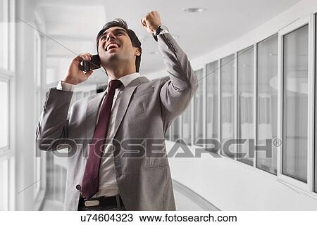 Smart young business man celebrating his success at office View Large Photo Image Stock Image - Smart young business man celebrating his success at office . Fotosearch