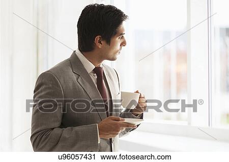 Stock Image - Smart young businessman taking coffee break at office . Fotosearch