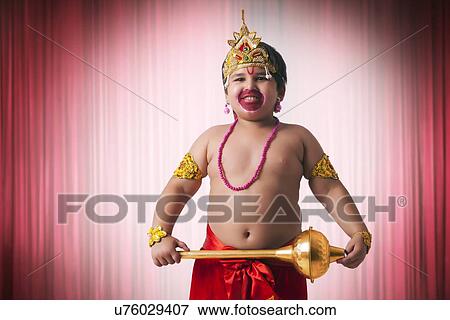 Stock Photo - Smiling boy dressed as God Hanuman against red theater curtain. Fotosearch