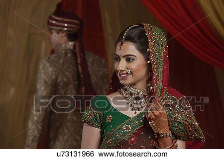 Stock Photograph - Smiling bride with husband in the background . Fotosearch