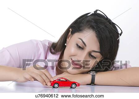 Smiling businesswoman looking at toy car against white background View Large Photo Image Stock Image - Smiling businesswoman looking at toy car against white background. Fotosearch