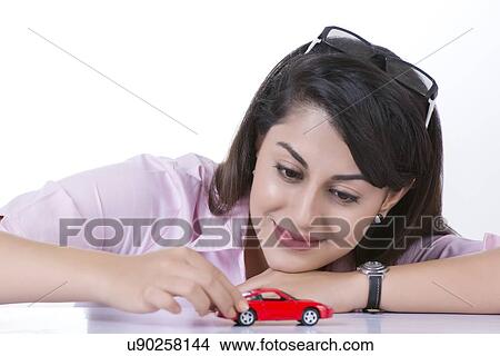Smiling businesswoman moving toy car against white background View Large Photo Image Picture - Smiling businesswoman moving toy car against white background. Fotosearch