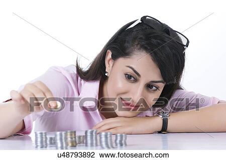 Smiling businesswoman stacking coins against white background View Large Photo Image Stock Image - Smiling businesswoman stacking coins against white background. Fotosearch
