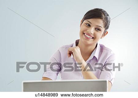 Smiling businesswoman using laptop over colored background View Large Photo Image Stock Photo - Smiling businesswoman using laptop over colored background . Fotosearch