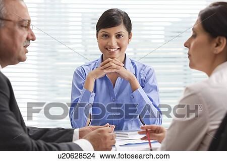 Smiling businesswoman with two executives discussing in office View Large Photo Image Picture - Smiling businesswoman with two executives discussing in office . Fotosearch