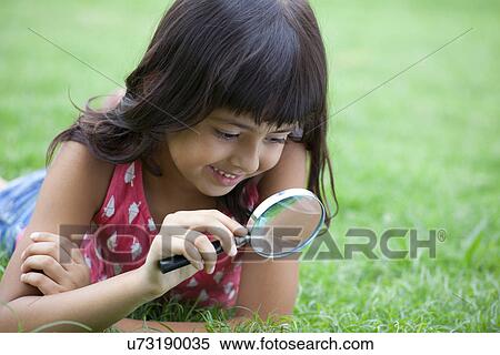 Smiling girl looking through magnifying glass View Large Photo Image Stock Photography - Smiling girl looking through magnifying glass . Fotosearch