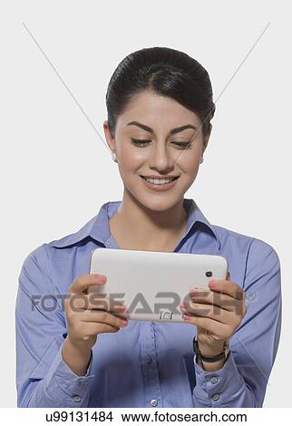 Picture - Smiling Indian businesswoman using tablet PC over white background. Fotosearch