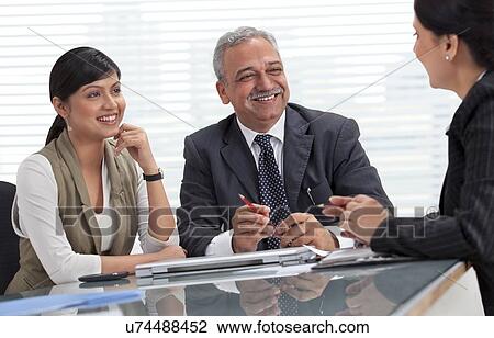 Smiling male and female professionals discussing in meeting View Large Photo Image Stock Image - Smiling male and female professionals discussing in meeting . Fotosearch