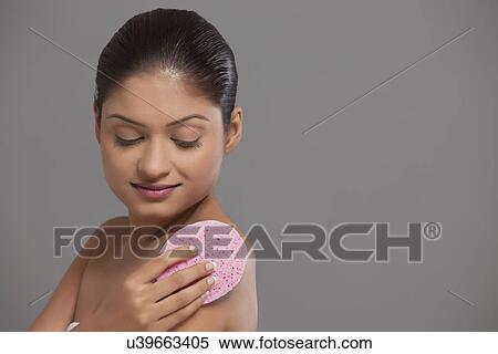 Stock Photography - Smiling woman using massage sponge . Fotosearch
