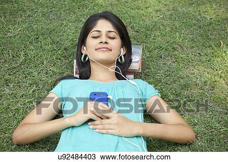 Stock Image - Smiling woman with eyes closed listening to music . Fotosearch