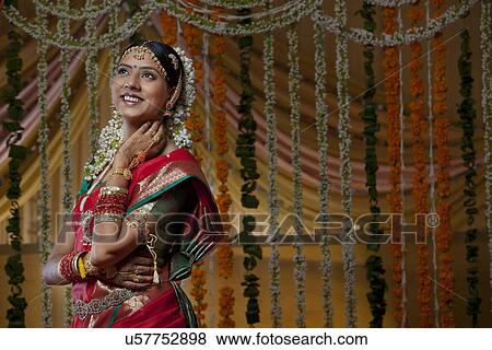 Smiling young bride looking away with flower decoration in background View Large Photo Image Stock Photo - Smiling young bride looking away with flower decoration in background . Fotosearch