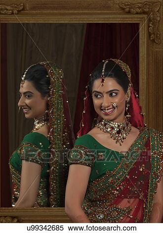 Stock Photography - Smiling young bride standing with mirror in the background . Fotosearch