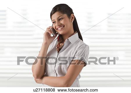 Stock Photo - Smiling young businesswoman speaking on phone call at office . Fotosearch