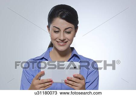 Smiling young businesswoman using digital tablet against gray background View Large Photo Image Stock Image - Smiling young businesswoman using digital tablet against gray background. Fotosearch