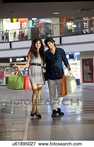 Smiling young couple walking in shopping mall View Large Photo Image Stock Photo - Smiling young couple walking in shopping mall . Fotosearch