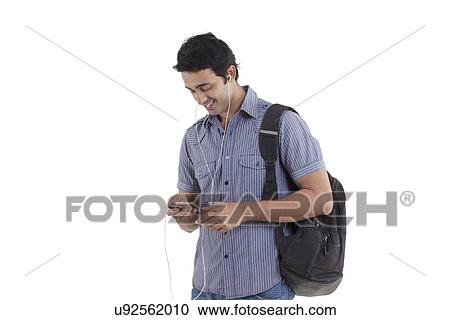 Stock Image - Smiling young man listening to music . Fotosearch