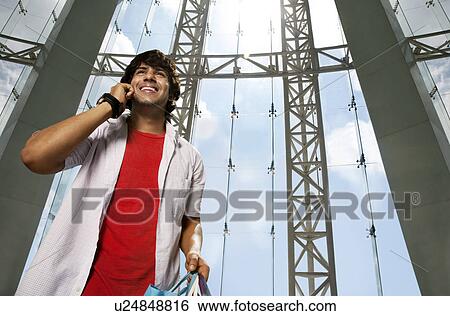 Smiling young man talking on the phone View Large Photo Image Stock Photograph - Smiling young man talking on the phone . Fotosearch