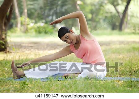 Stock Photo - Smiling young woman doing stretching exercise . Fotosearch