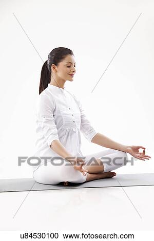 Stock Image - Smiling young woman in lotus position . Fotosearch