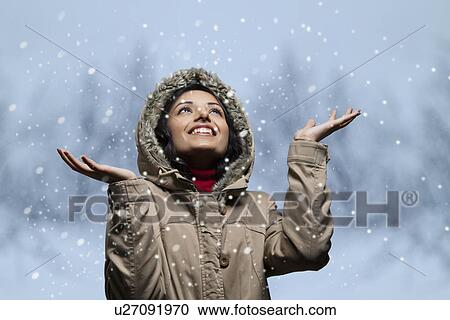 Smiling young woman looking up and enjoying snow fall View Large Photo Image Stock Image - Smiling young woman looking up and enjoying snow fall . Fotosearch