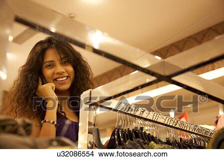Picture - Smiling young woman on call at clothing store . Fotosearch