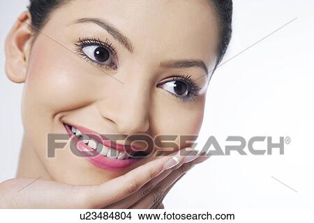 Picture - Smiling young woman with hand on chin looking away . Fotosearch