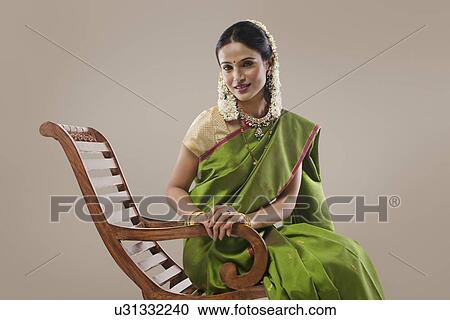 Stock Image - South Indian woman sitting on an arm chair . Fotosearch