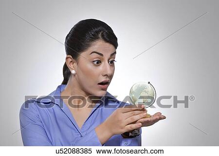 Surprised businesswoman looking at crystal globe over gray background View Large Photo Image Stock Photography - Surprised businesswoman looking at crystal globe over gray background. Fotosearch