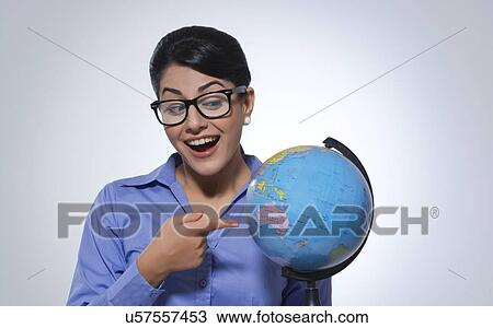 Surprised businesswoman pointing at globe over gray background View Large Photo Image Stock Image - Surprised businesswoman pointing at globe over gray background. Fotosearch