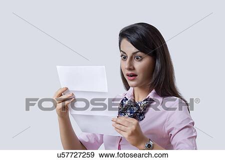 Surprised businesswoman reading document over gray background View Large Photo Image Stock Photo - Surprised businesswoman reading document over gray background. Fotosearch