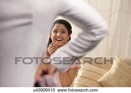 Surprised woman looking at man holding gift View Large Photo Image Stock Image - Surprised woman looking at man holding gift . Fotosearch