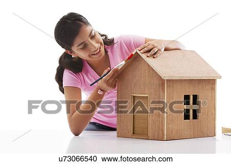 Stock Image - Teenage girl painting a wooden house . Fotosearch