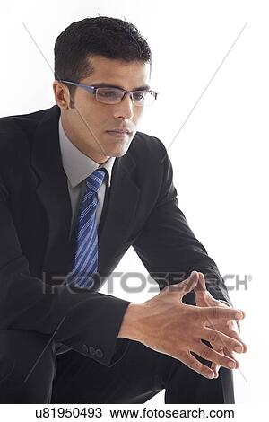 Stock Image - Thoughtful businessman with hands clasped over white background . Fotosearch