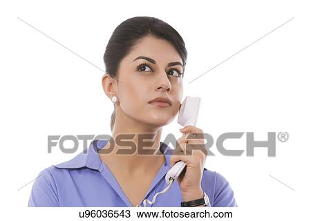 Thoughtful businesswoman holding telephone receiver against white background View Large Photo Image Stock Image - Thoughtful businesswoman holding telephone receiver against white background. Fotosearch