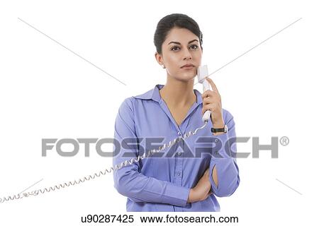Thoughtful businesswoman holding telephone receiver over white background View Large Photo Image Stock Photography - Thoughtful businesswoman holding telephone receiver over white background. Fotosearch