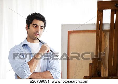 Thoughtful male painter standing in front of easel View Large Photo Image Stock Image - Thoughtful male painter standing in front of easel . Fotosearch