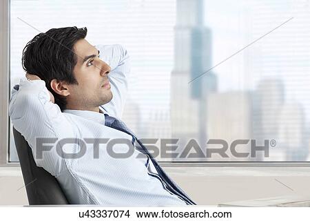 Thoughtful young business man relaxing on office chair View Large Photo Image Picture - Thoughtful young business man relaxing on office chair . Fotosearch