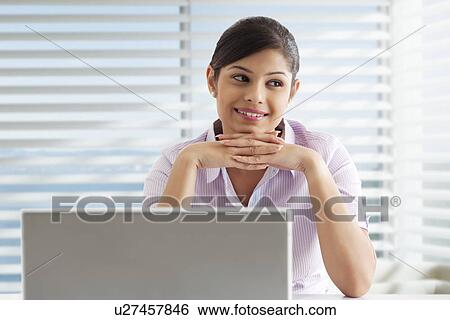Thoughtful young female executive with laptop at office View Large Photo Image Stock Photograph - Thoughtful young female executive with laptop at office . Fotosearch