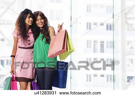 Stock Image - Two beautiful friends enjoying while shopping . Fotosearch